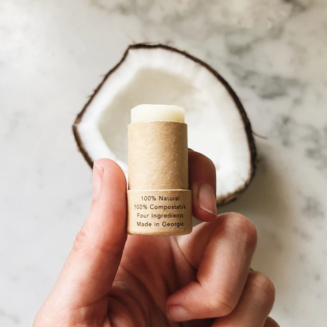 open lip balm in front of coconut